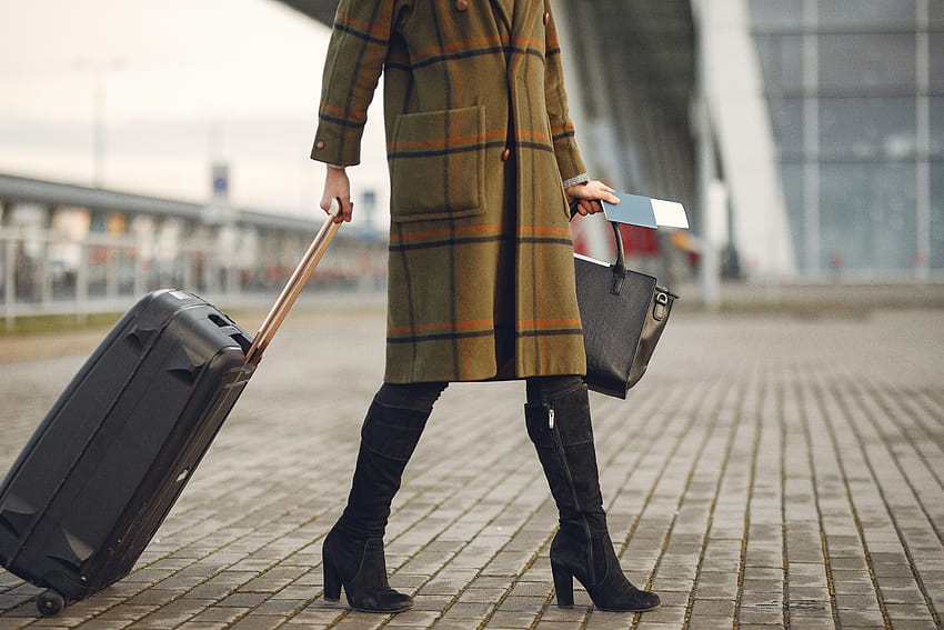 Mulher vestindo um casaco segurando uma bolsa de bagagem preta · Estoque, bagagem feminina papel de parede HD