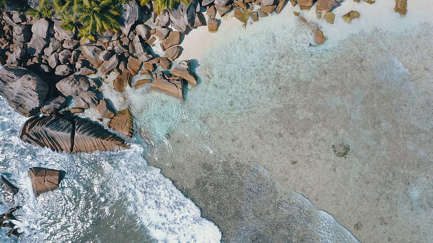 vue aérienne des s verticales d'eau peu profonde turquoise cristalline et d'incroyables rochers de granit sur la plage tropicale de l'île de La Digue Séquence Vidéo Fond d'écran HD