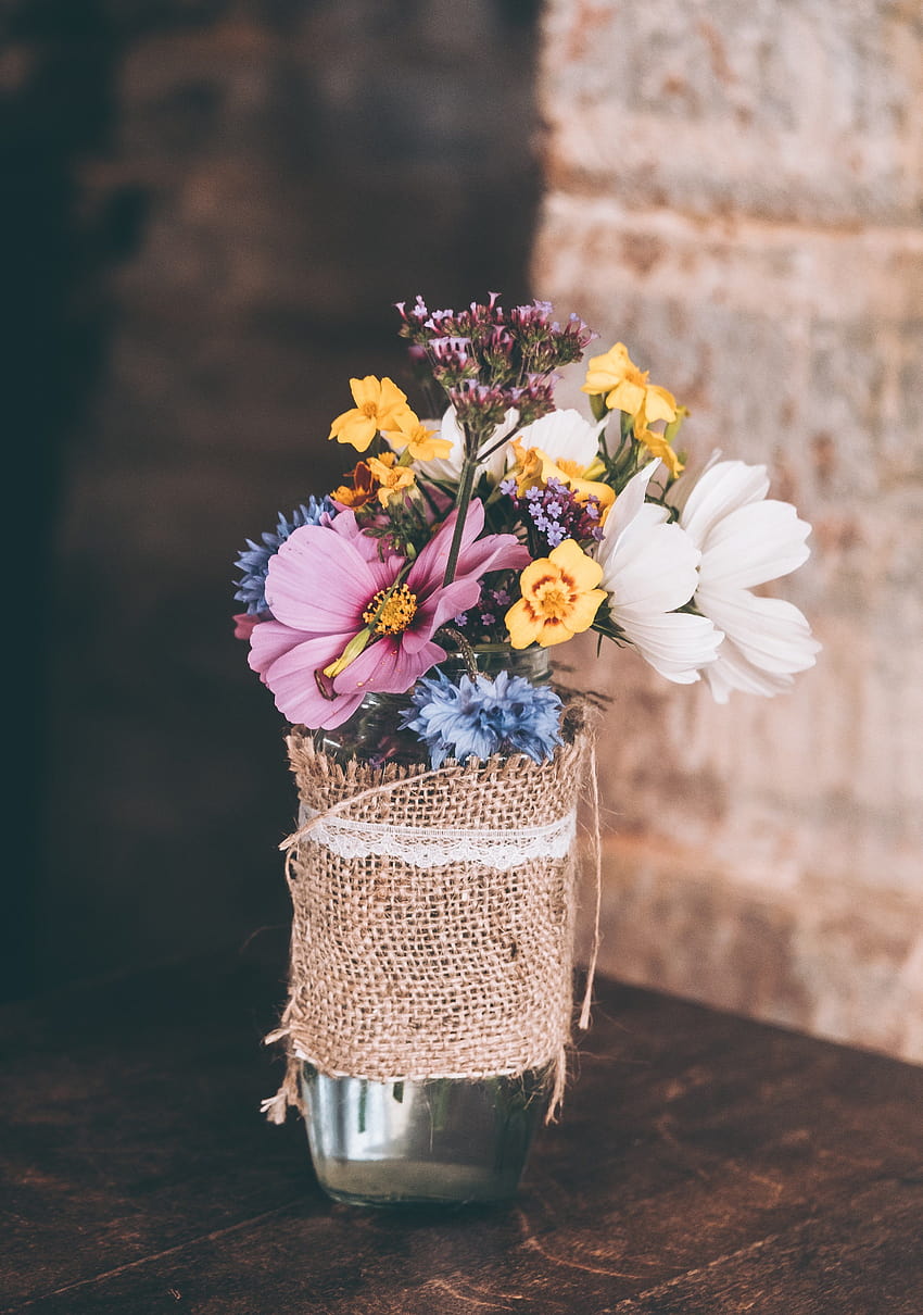 A bouquet of various flowers in a glass vase on a wooden, flower vase