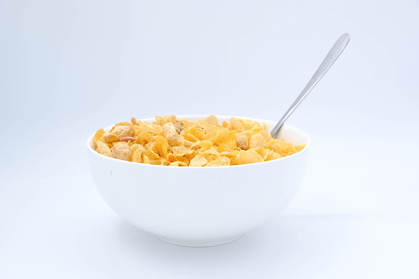 Recipiente con copos de maíz y una cuchara sobre s blancos · Caldo, copos helados fondo de pantalla