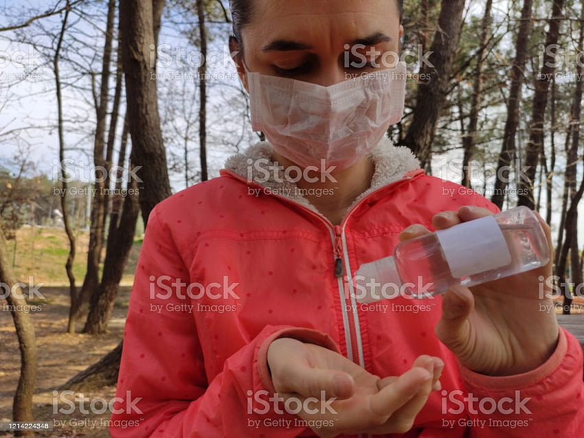 Kobieta w płaszczu zimowym z maską ochronną na twarzy przy użyciu zapasu środka dezynfekującego do rąk, zimowego środka dezynfekującego Tapeta HD