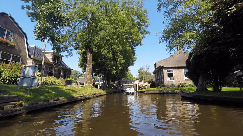 Giro in barca a motore nel canale principale del famoso villaggio di Giethoorn Sfondo HD
