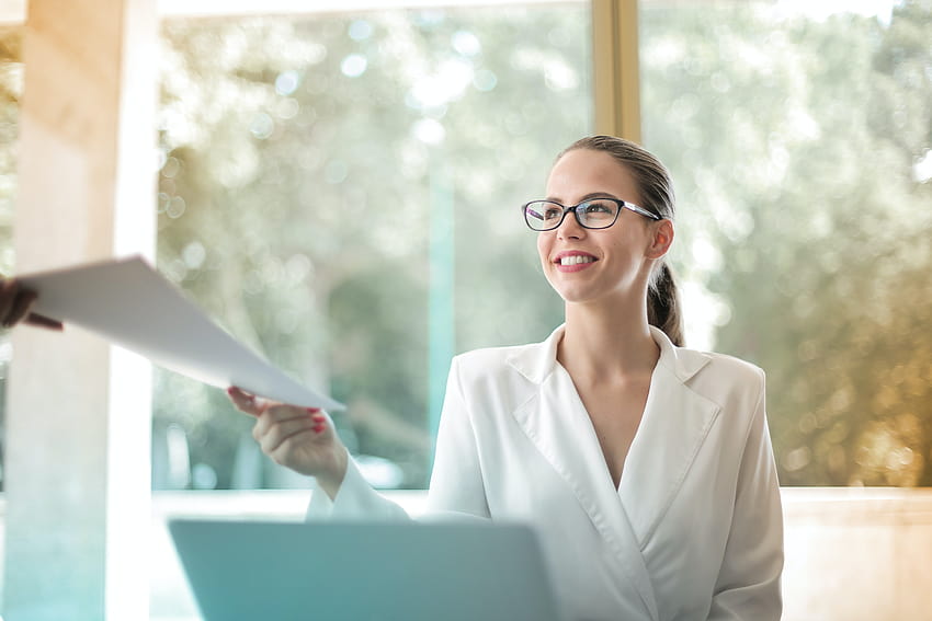 Positive Geschäftsfrau, die Papierkram im Büro erledigt · Lager, Büroangestellter HD-Hintergrundbild