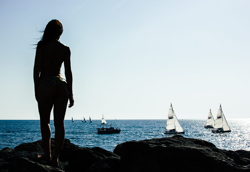 Жена, стояща на скала с ветроходни лодки в морето · Запас, момиче и лодка HD тапет