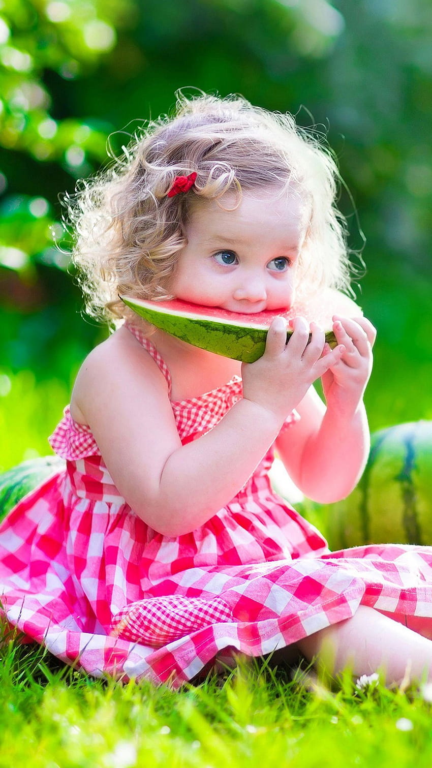 Cute Baby Girl è seduto sull'erba verde mangiare anguria indossando abito rosa Bambina carina e carina Sfondo del telefono HD