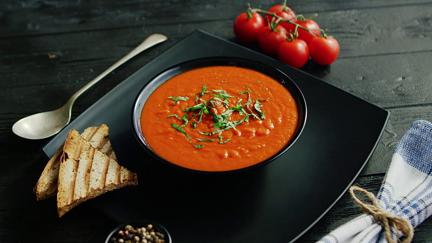 From above view of tomato soup in black bowl sprinkled with herb served with crisp bread on wooden backgrounds Stock Video Footage HD wallpaper