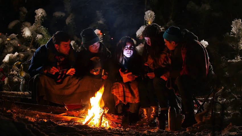Group of friends in winter forest. Sitting near the bonfire wrapped in a blanket, listening a story and get scared Stock Video Footage, winter camp fire HD wallpaper
