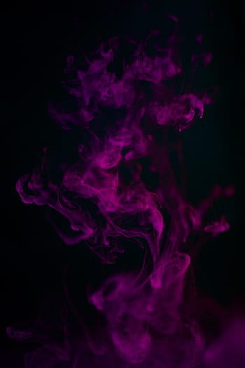 A person in a black hoodie with obscured face holds up a pink smoke ...