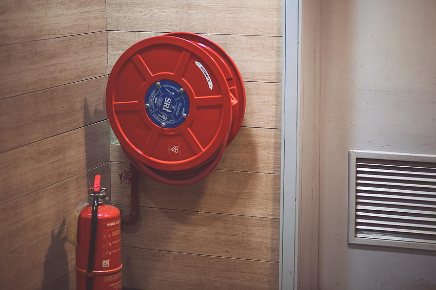 Червен пожарогасител до макара за маркуч вътре в стаята ·, противопожарни аларми HD тапет
