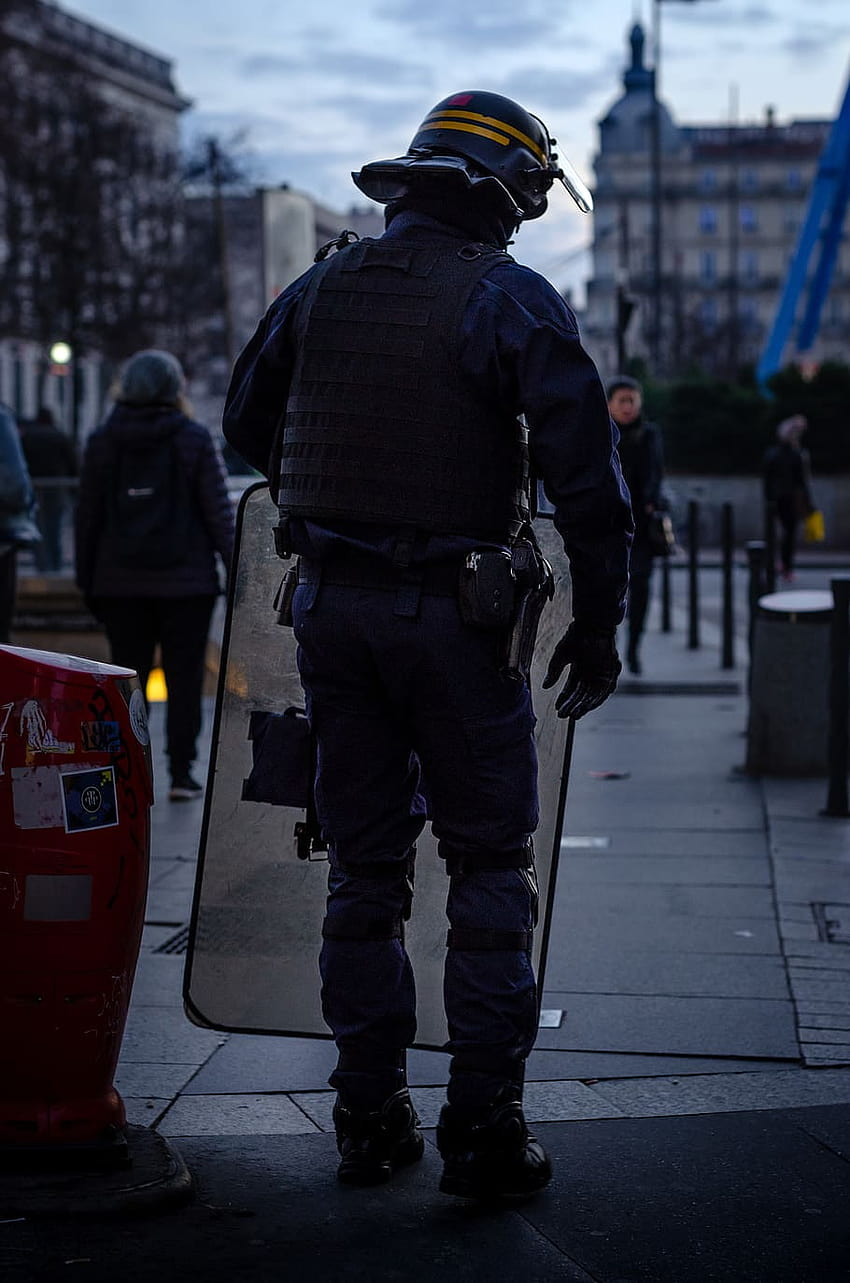 : oficial de policía de pie y portando escudo antidisturbios, oficial de policía móvil fondo de pantalla del teléfono