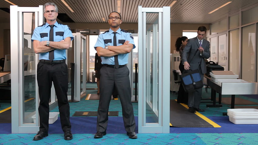 2501440 numaralı metal dedektörün önünde duran iki havaalanı güvenlik görevlisi Stok Video, Vecteezy'de HD duvar kağıdı