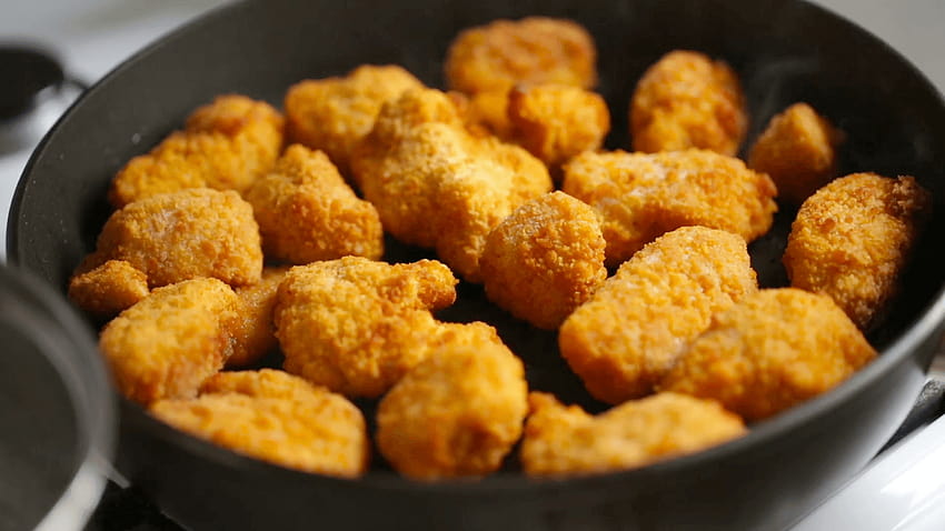 Wooden shovel stirs chicken nuggets in a frying pan Stock Video HD wallpaper