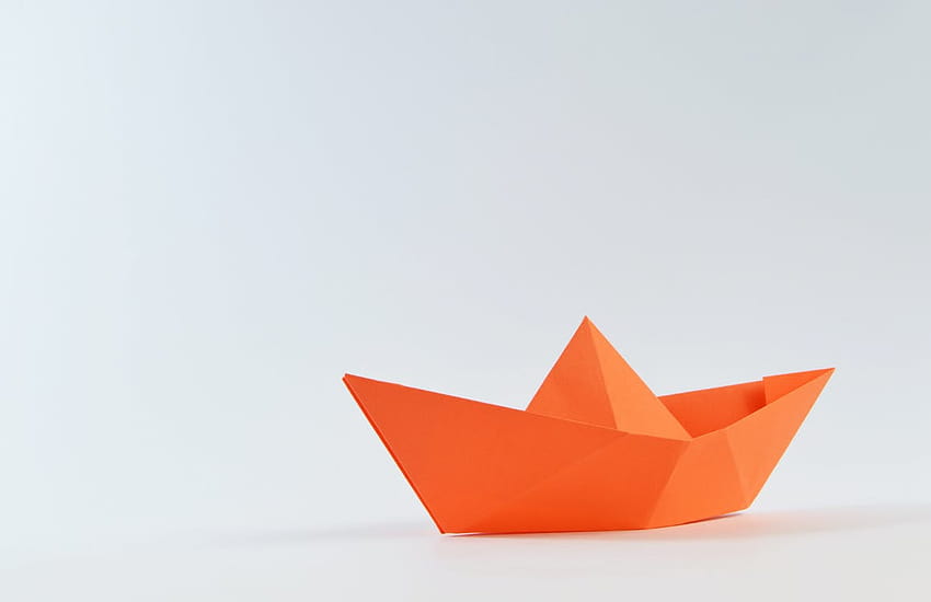 Barca di carta arancione su superficie bianca · Stock Sfondo HD