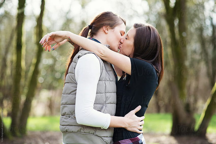 Attraktives junges lesbisches Paar küsst sich im Park von Kate Ames, lesbischer Kuss HD-Hintergrundbild