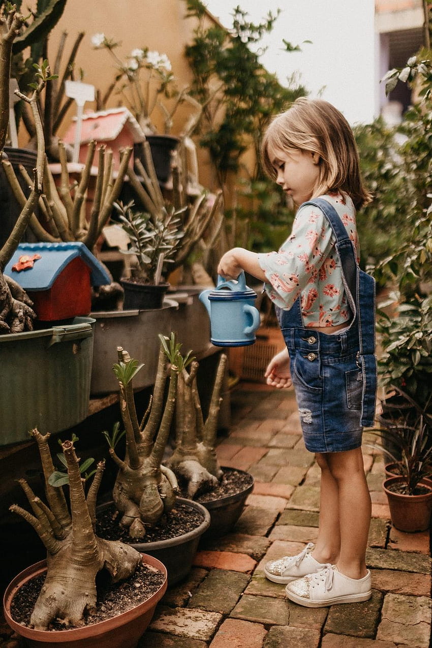 girl wearing blue romper holding teal watering can HD phone wallpaper