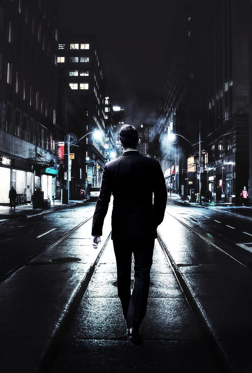 Млад мъж, облечен в бизнес костюм, който върви по улицата през нощта HD тапет за телефон