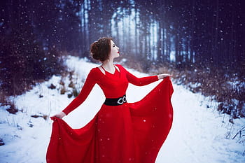 Young Redhead Girl In Flowing Red Dress In Forest With Snowfall