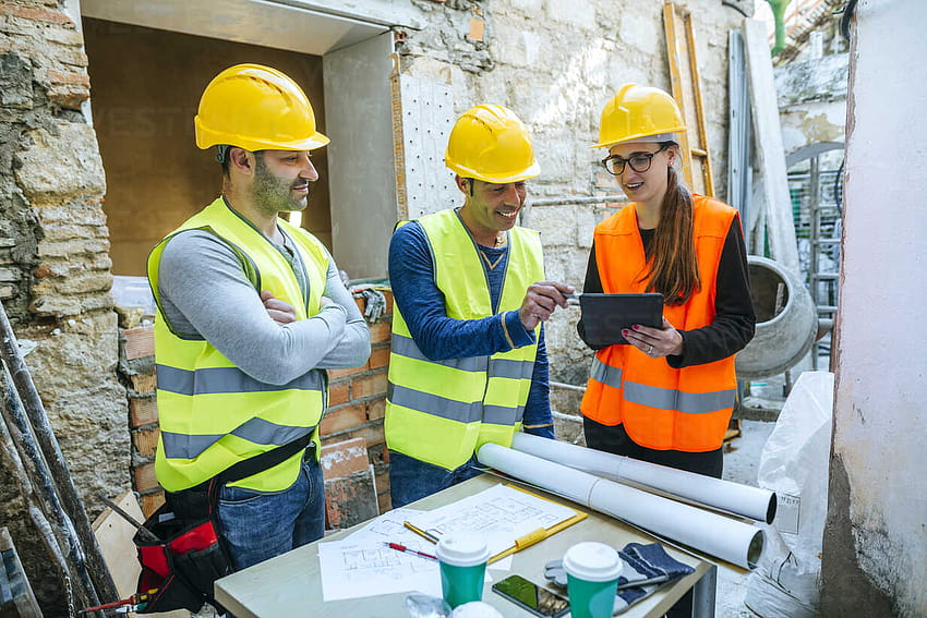 Femme et deux ouvriers du bâtiment avec tablette sur le stock de chantier Fond d'écran HD