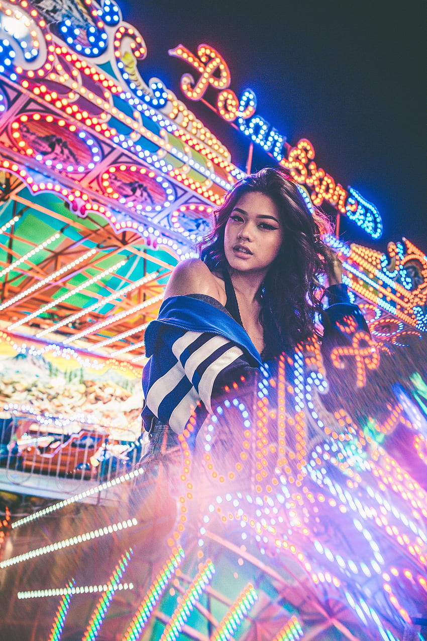 a woman stands among bright neon lights at a carnival in, light neon girl HD phone wallpaper