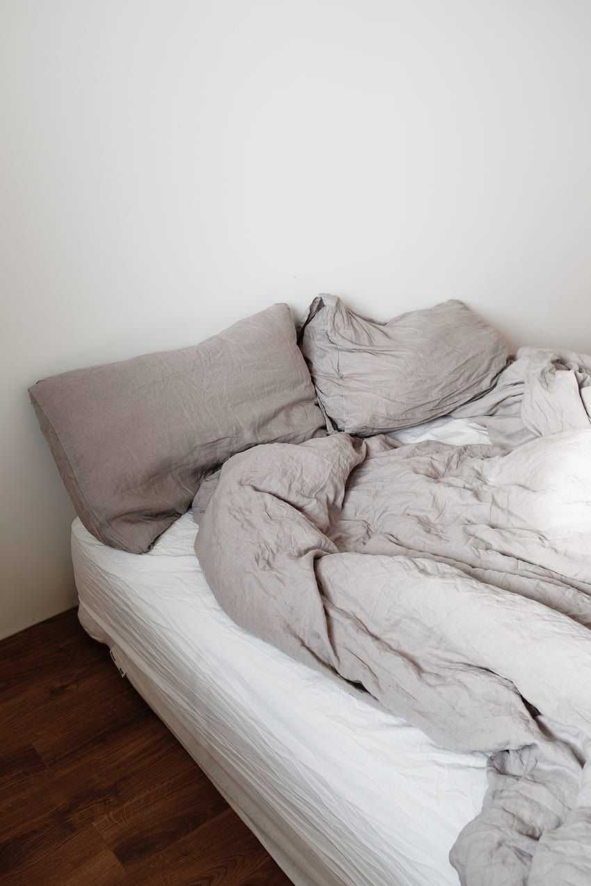 Letto disfatto con cuscini e coperta in camera da letto luminosa · Magazzino, materasso Sfondo del telefono HD