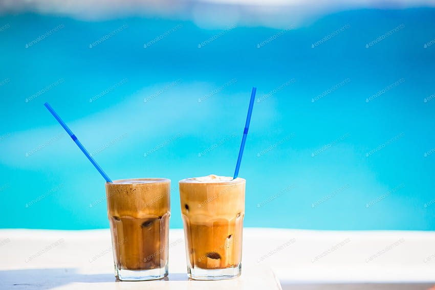 フラッペ、ビーチでアイスコーヒー。 Envato Elements の travnikovstudio による背の高いグラスに入った夏のアイス コーヒー フラペチーノ、フラッペまたはラテ、 高画質の壁紙