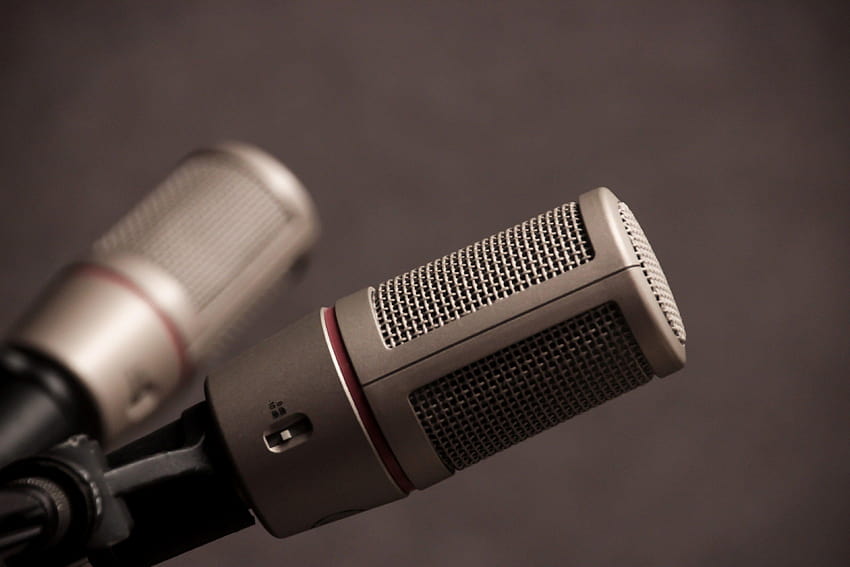 dos micrófonos grises en un punto de soporte en direcciones opuestas fondo de pantalla