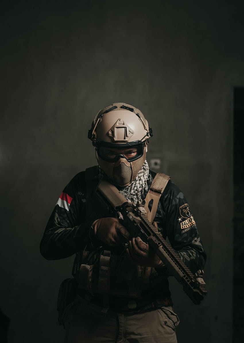Un hombre vestido con un uniforme militar sosteniendo un arma de fuego · Stock, uniforme táctico negro fondo de pantalla del teléfono