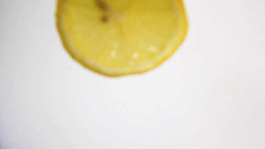 Piece of fresh yellow lemon falling down into fresh white milk with explosive beautiful splash. Shot in slow motion mode on high HD wallpaper