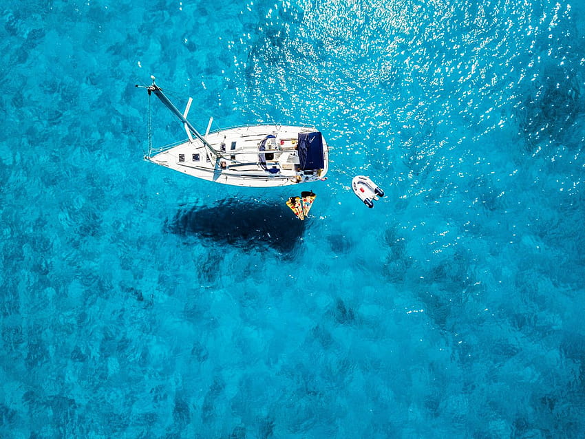Ein ruhendes Segelboot auf kristallklarem Wasser HD-Hintergrundbild