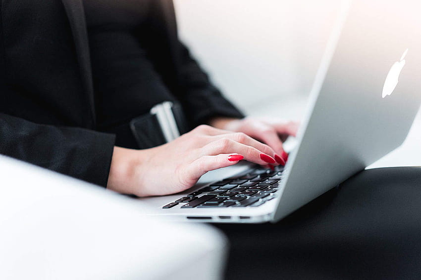 Geschäftsfrau, die auf MacBook Stock tippt, weibliche Angestellte HD-Hintergrundbild