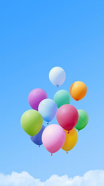 A pair of colorful round balloons float weightlessly over a blurred  background, orb shapes providing a