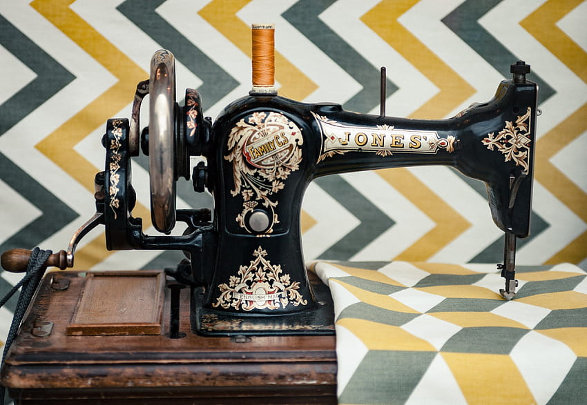 the side view of an old vintage sewing machine sewing on a patterned HD wallpaper