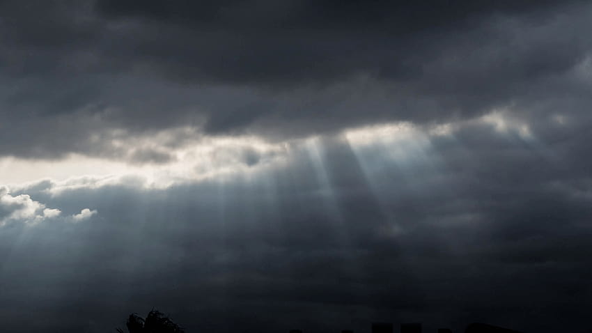 Rays of sunlight shining through rainy storm clouds background. HD wallpaper