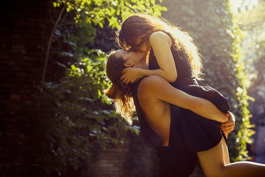 Side view of loving young couple kissing on mouth against sky stock photo