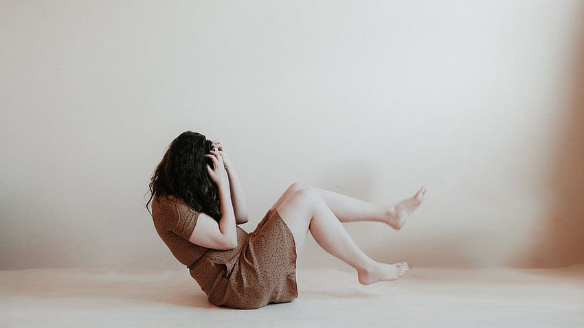 女の子は髪で覆われた顔のうつ病で床に座っています。 高画質の壁紙