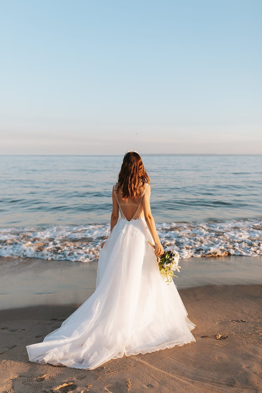 ผู้หญิงในชุดแต่งงานสีขาวยืนอยู่บนชายหาดในเวลากลางวัน – งานแต่งงาน, ชุดแต่งงาน วอลล์เปเปอร์โทรศัพท์ HD