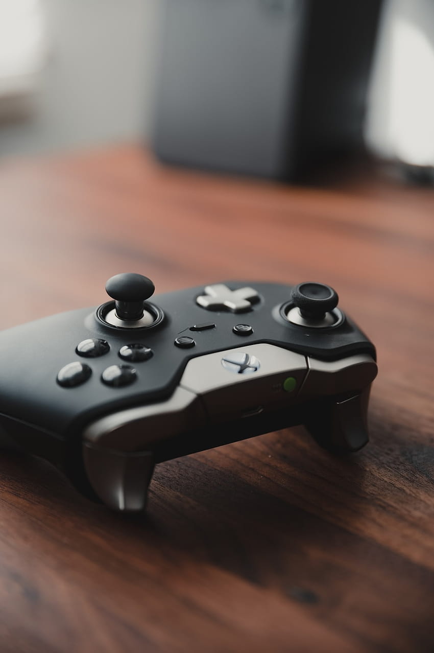Schwarzer Xbox-Gamecontroller auf braunem Holztisch – Elite-Controller HD-Handy-Hintergrundbild