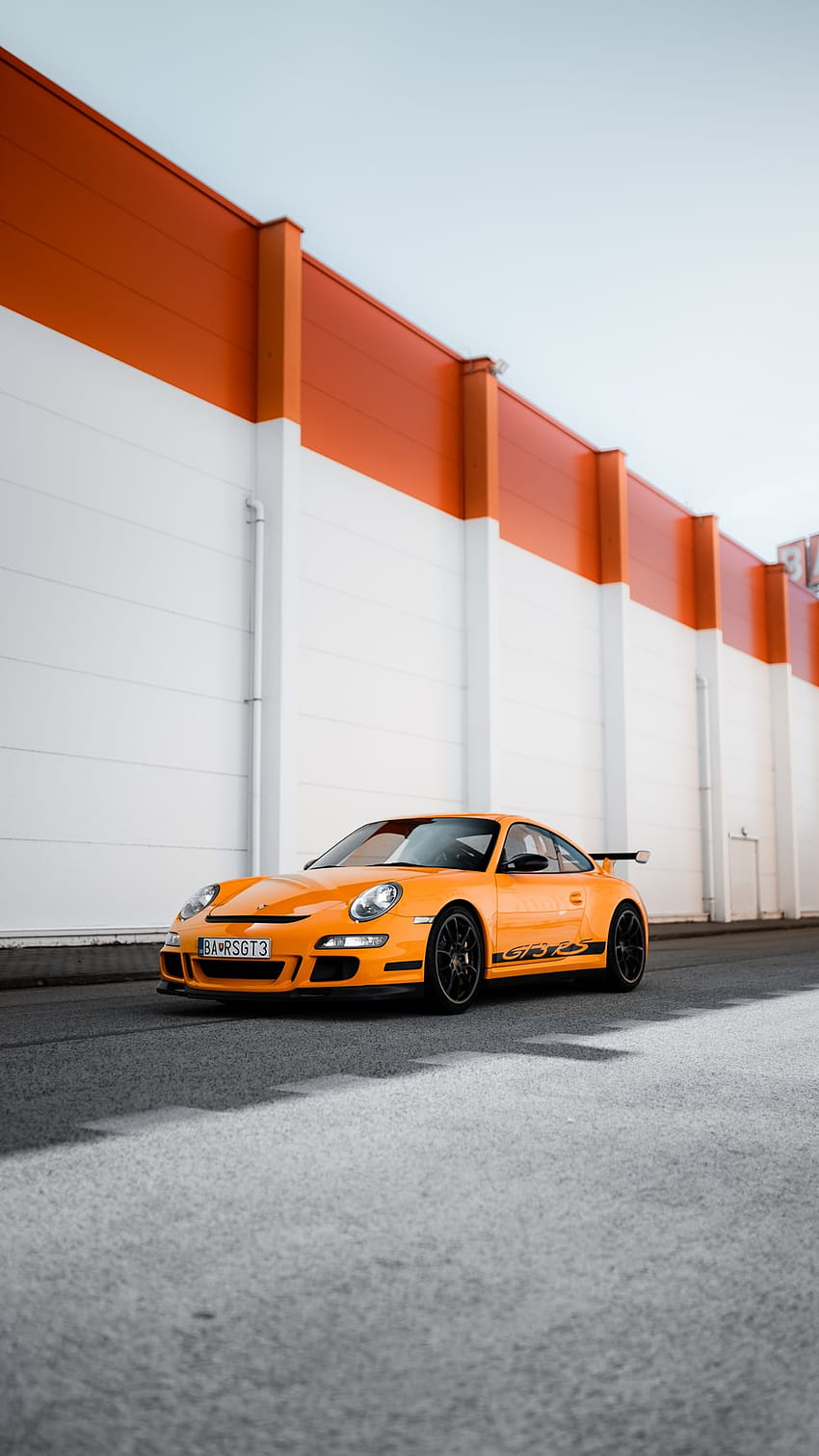 Orange-schwarzer Porsche 911 parkt neben weiß-roter Wand – 911 gt HD-Handy-Hintergrundbild