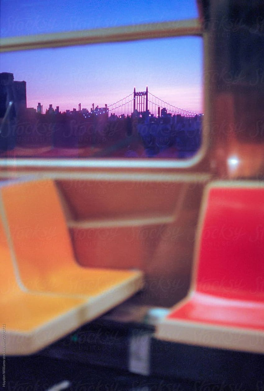 Die bunten Sitze einer leeren New Yorker U-Bahn mit Blick aus dem Fenster auf die Stadt in der Abenddämmerung … HD-Handy-Hintergrundbild