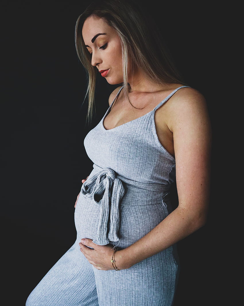 Eine schwangere Frau, die einen grauen ärmellosen Strampler trägt · Stock, schwangere Frauen HD-Handy-Hintergrundbild