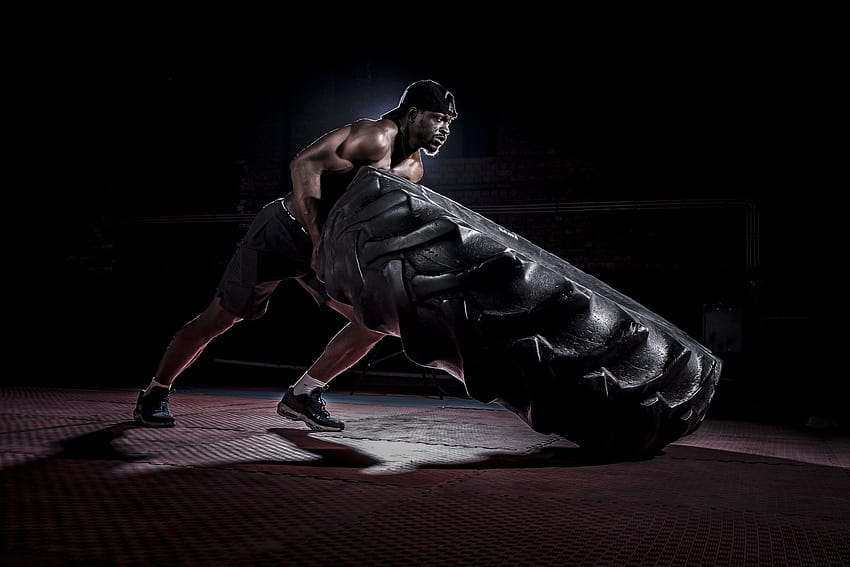 Strong shirtless black man flipping heavy tire in dark gym · Stock, gym black HD wallpaper