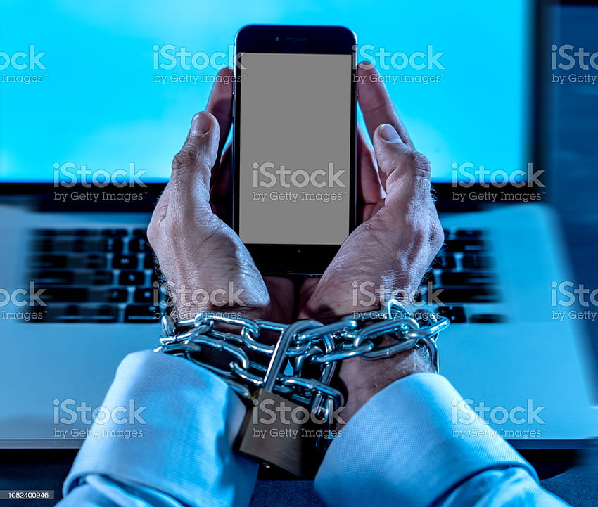 ✓ Млад мъж, пристрастен към мобилния телефон, ръцете са вързани и заключени с желязна метална верига с катинар на китките в смарт телефон, пристрастяване към интернет и социални медии и жертва на робска технология HD тапет