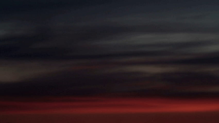 Statische Zeitrafferaufnahme mit mittlerem Weitwinkel und niedrigem Winkel von dunkelgrauen Wolken beleuchtet, dunkelgrauer Hintergrund HD-Hintergrundbild
