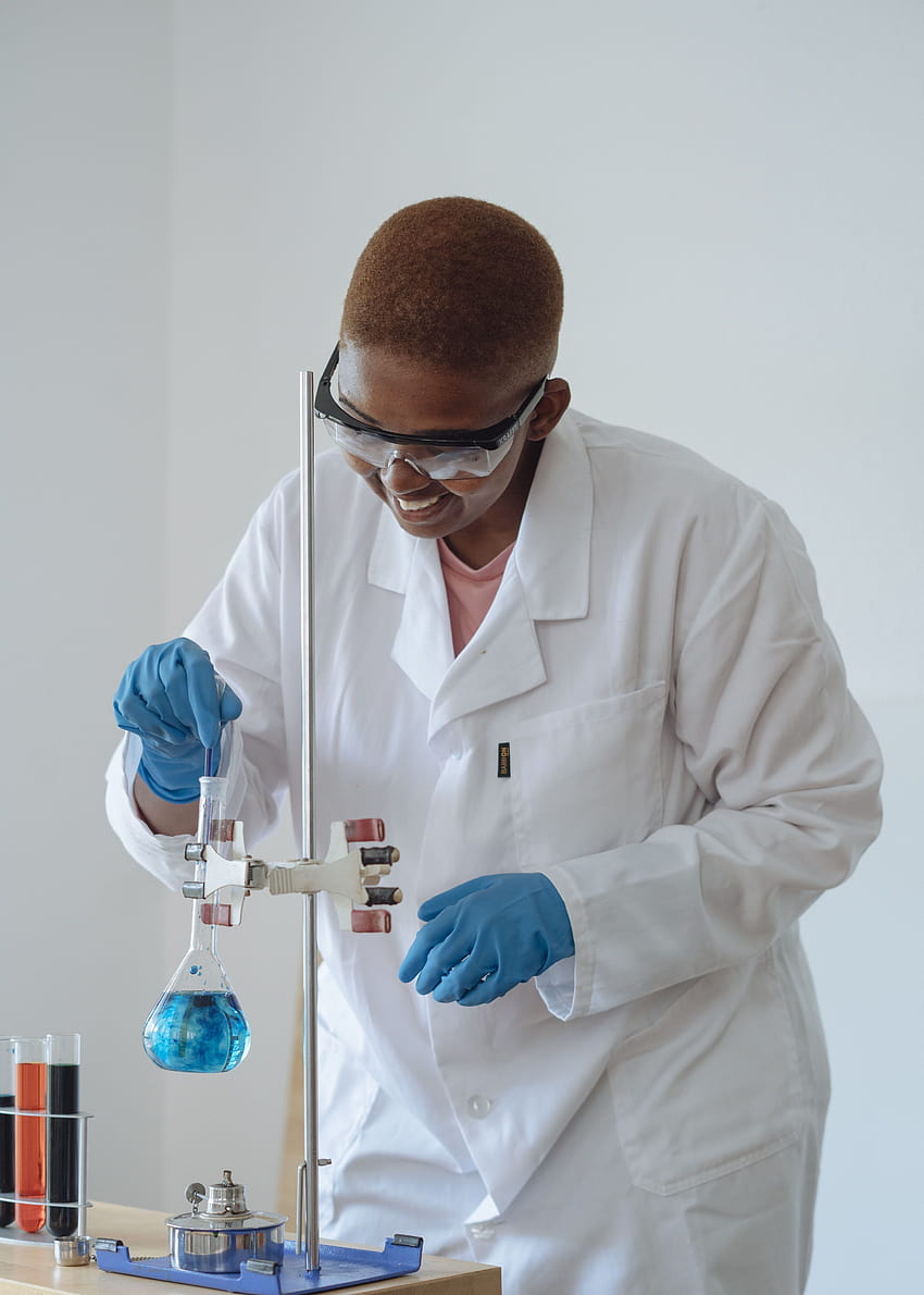 Smiling scientist examining chemical liquid in modern lab · Stock, scientist lab coat HD phone wallpaper
