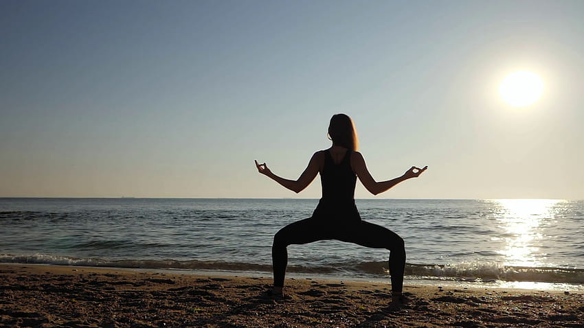 Beautiful young woman practicing morning yoga on sand sea beach. Surya Namaskar, sun salutation HD wallpaper