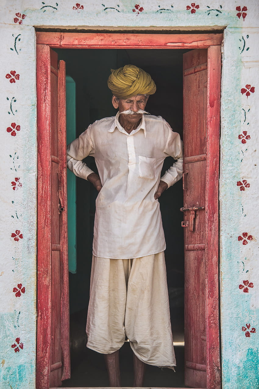 ID: 255565 / indian man with flowy clothes and a yellow turban standing in a pink doorway with flower on the walls, indian man standing in doorway HD phone wallpaper