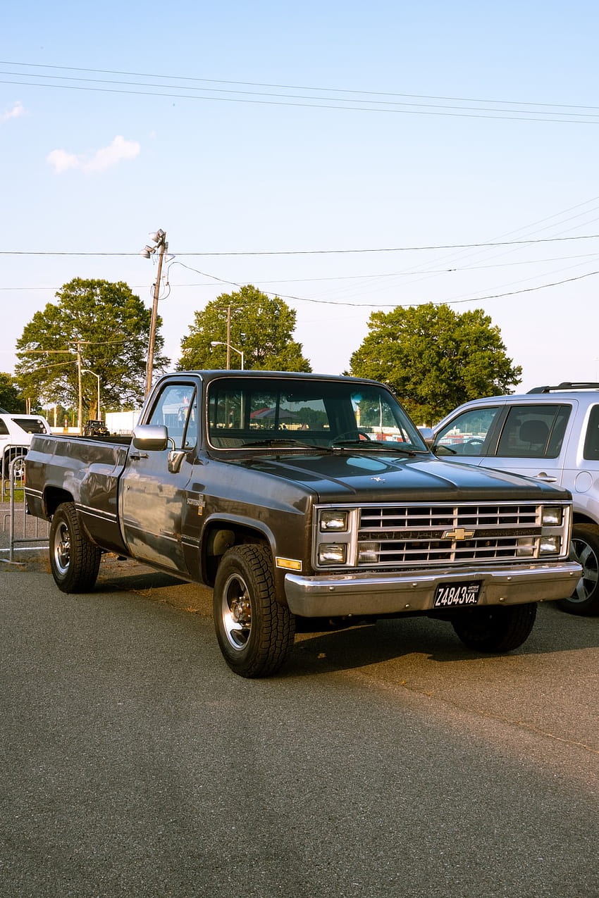 Blauer Chevrolet-Pickup mit Einzelkabine, der tagsüber auf einer grauen Betonstraße geparkt ist – LKW HD-Handy-Hintergrundbild