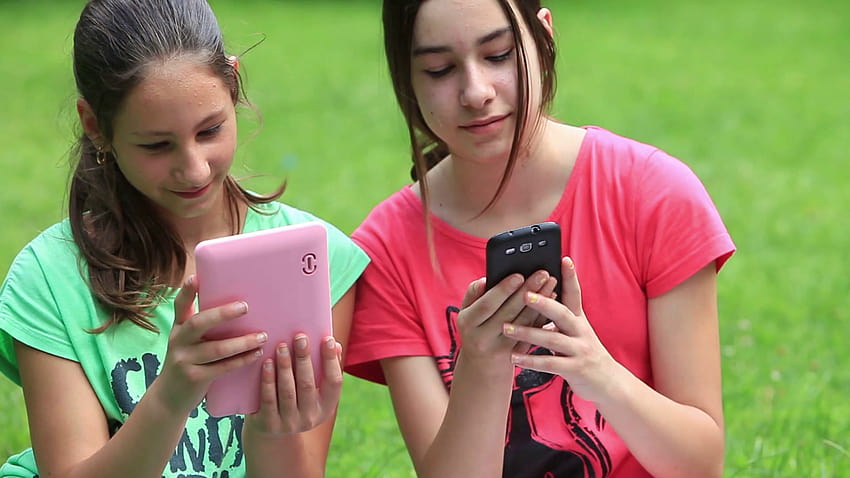 Two girls sitting on a meadow and showing eachother some on their devices and giggling... Stock Video Footage, girls giggling HD wallpaper