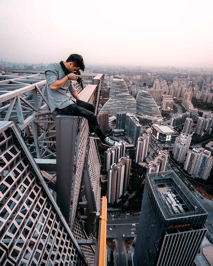 아래에서 촬영하는 건물 꼭대기에 앉아있는 남자 - 베이징, 마천루에 앉아 HD 전화 배경 화면